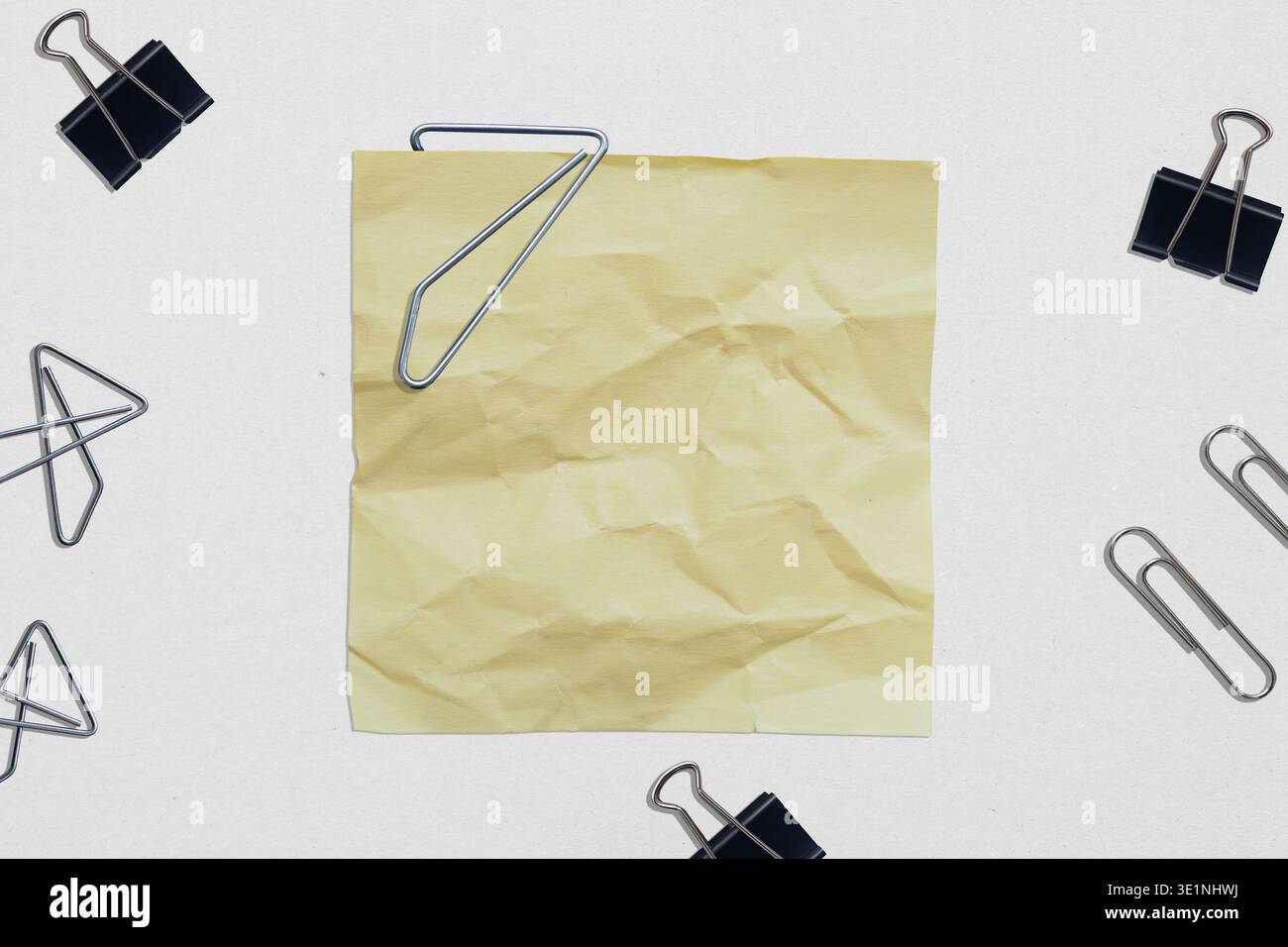 Nota di carta arricciata gialla con varie clip sulla scrivania bianca Foto Stock