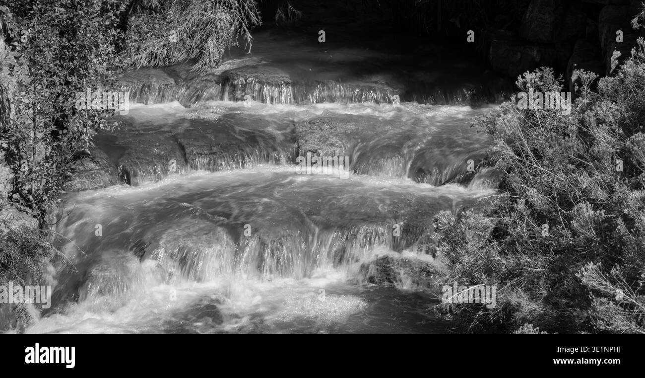 immagine in bianco e nero dell'acqua che cade sulle rocce scattata con una velocità dell'otturatore ridotta per mostrare il movimento e il flusso dell'immagine orizzontale con spazio per la molla tipo Foto Stock