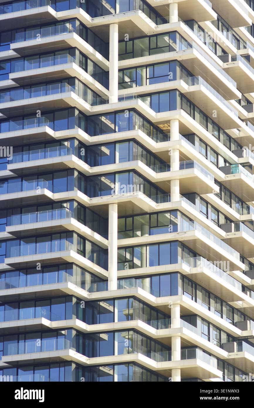 Balconi in vetro sfalsati della torre contemporanea. Illustra la progettazione parametrica delle facciate, il ritmo architettonico e lo sviluppo residenziale di livello premium. Foto Stock