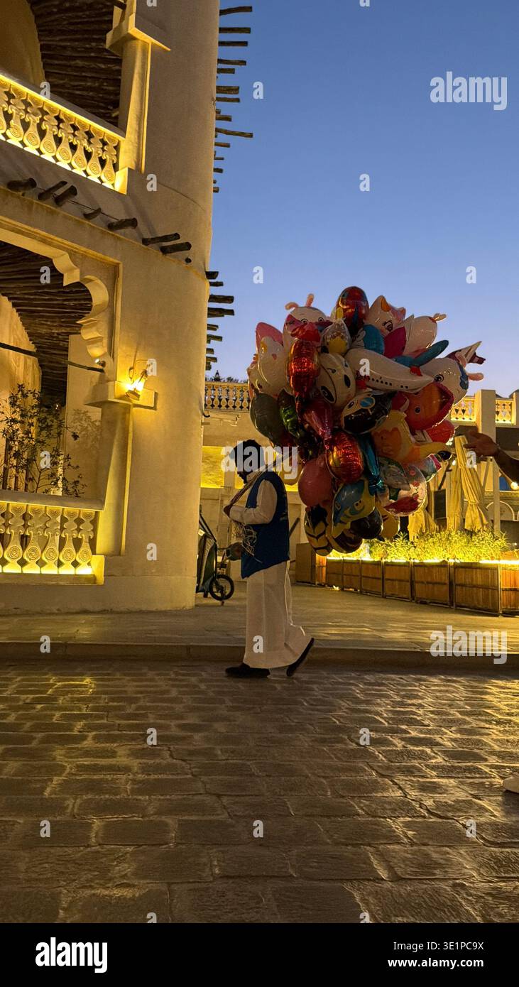 Uomini con palloncini colorati vicino all'architettura tradizionale di Doha, Qatar. - Immagine stock catturata con smartphone