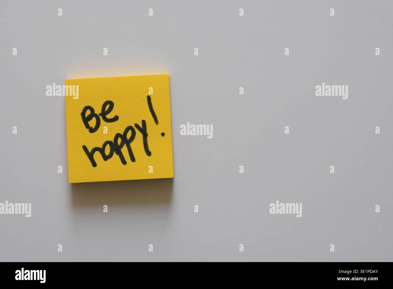 Nota adesiva gialla con la frase Be Happy scritta sopra, che rappresenta positività, motivazione, felicità e benessere mentale. Foto Stock