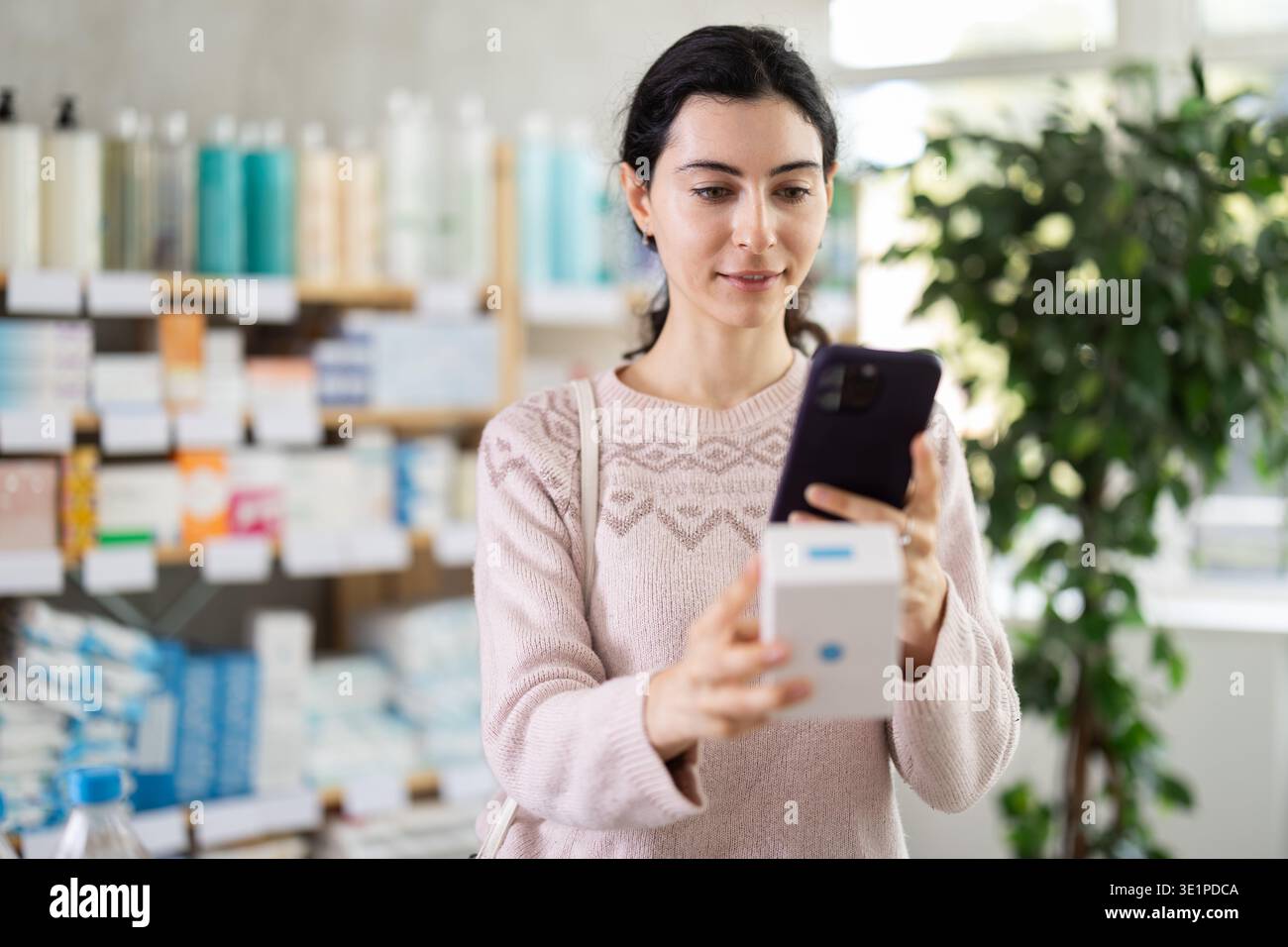 Ragazza in abiti autunnali scansiona il codice sulla confezione di pillole per controllare la data di scadenza Foto Stock