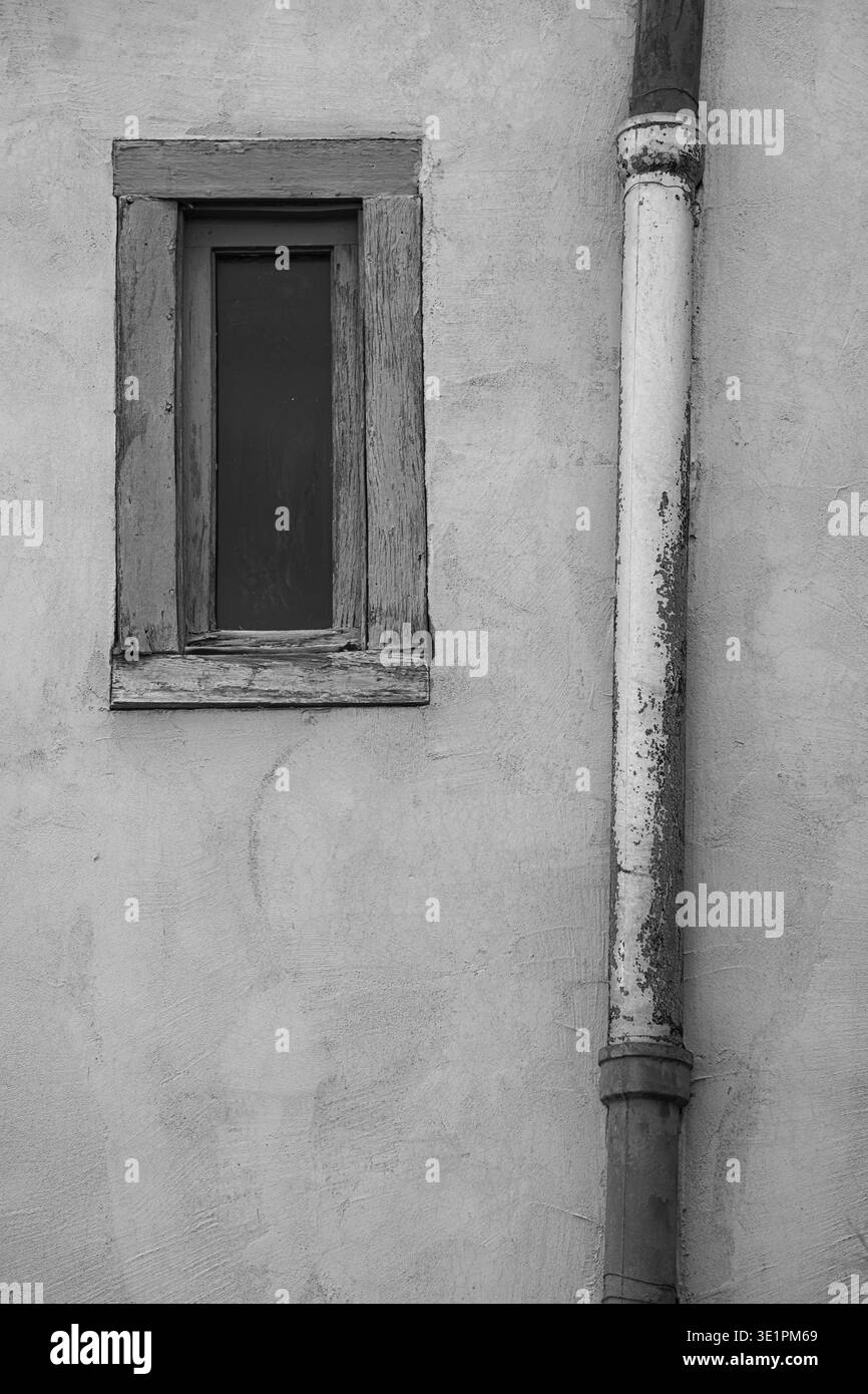 Bianco e nero di pipa arrugginita e vecchia finestra in legno sulle pareti esterne di un vecchio edificio in stile adobe casa a Santa Fe, New Mexico, turismo di viaggio verticale Foto Stock