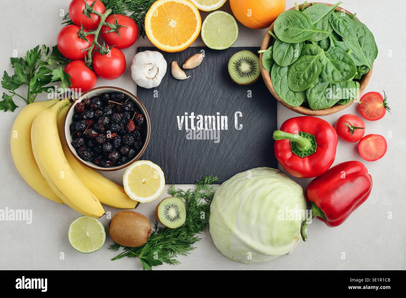 Alimenti sani contenenti vitamina C (acido ascorbico). Fonti naturali di vitamina C su sfondo chiaro con lavagna, vista dall'alto. Foto Stock