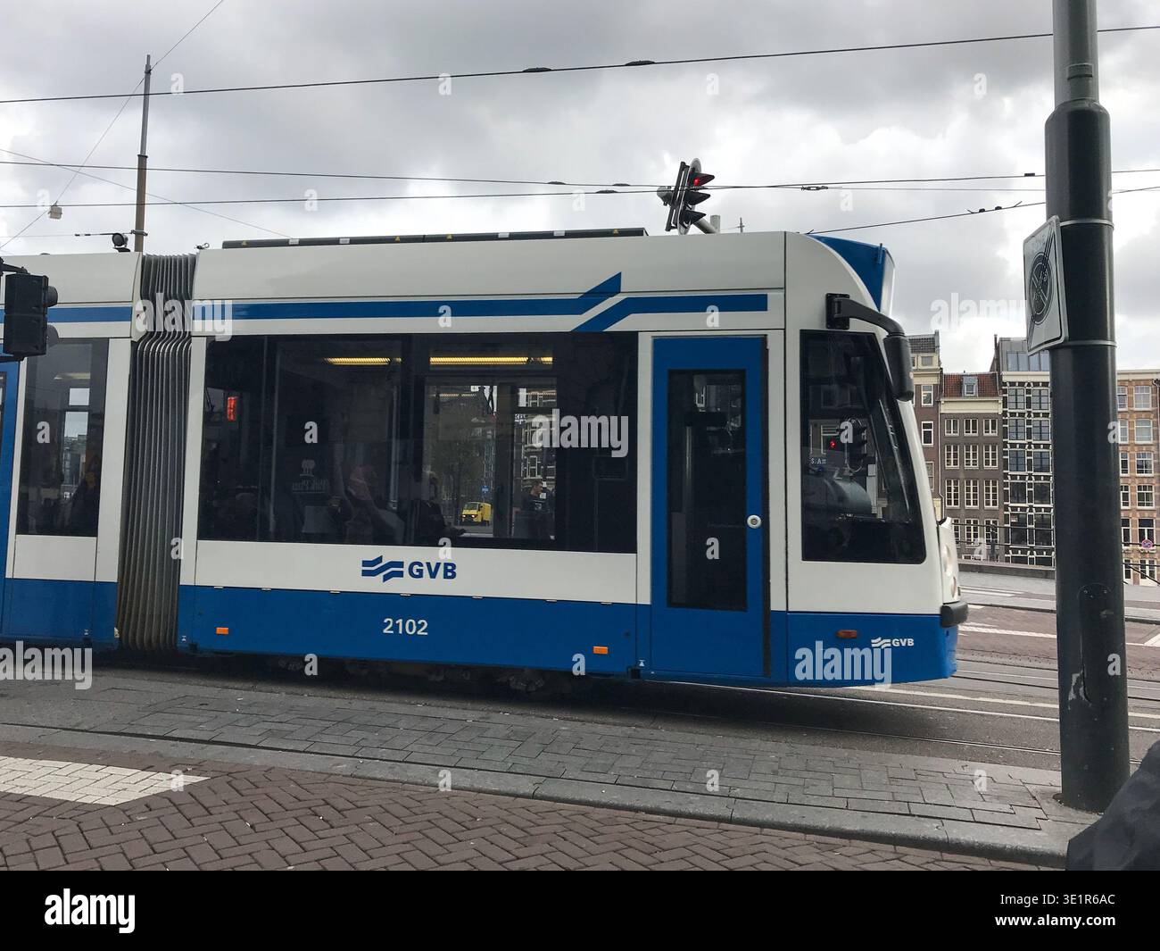 Un tram che si muove nella cornice lungo una strada principale di Amsterdam, passando davanti alle famose case storiche sui canali. Trasporto urbano nella capitale Foto Stock