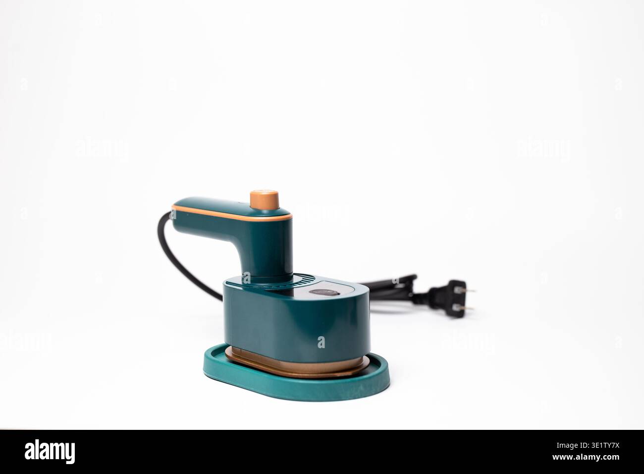 Ferro da stiro portatile moderno e compatto per indumenti da viaggio color tè con impugnatura ergonomica, dettagli in tonalità oro e base ovale stabile. Foto Stock