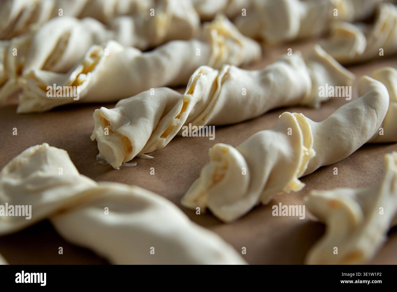 Pezzi di pasta sfoglia disposti ordinatamente su una teglia da forno rivestita con carta pergamena, pronti per la preparazione Foto Stock