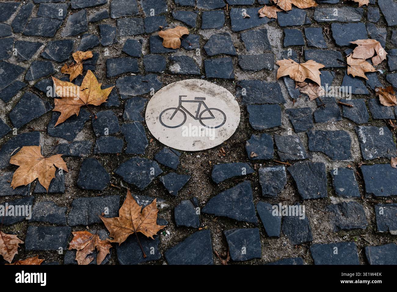Piccolo cartello rotondo con il simbolo di una bicicletta che indica una pista ciclabile su una strada acciottolata a Lisbona, Portogallo. Foto Stock
