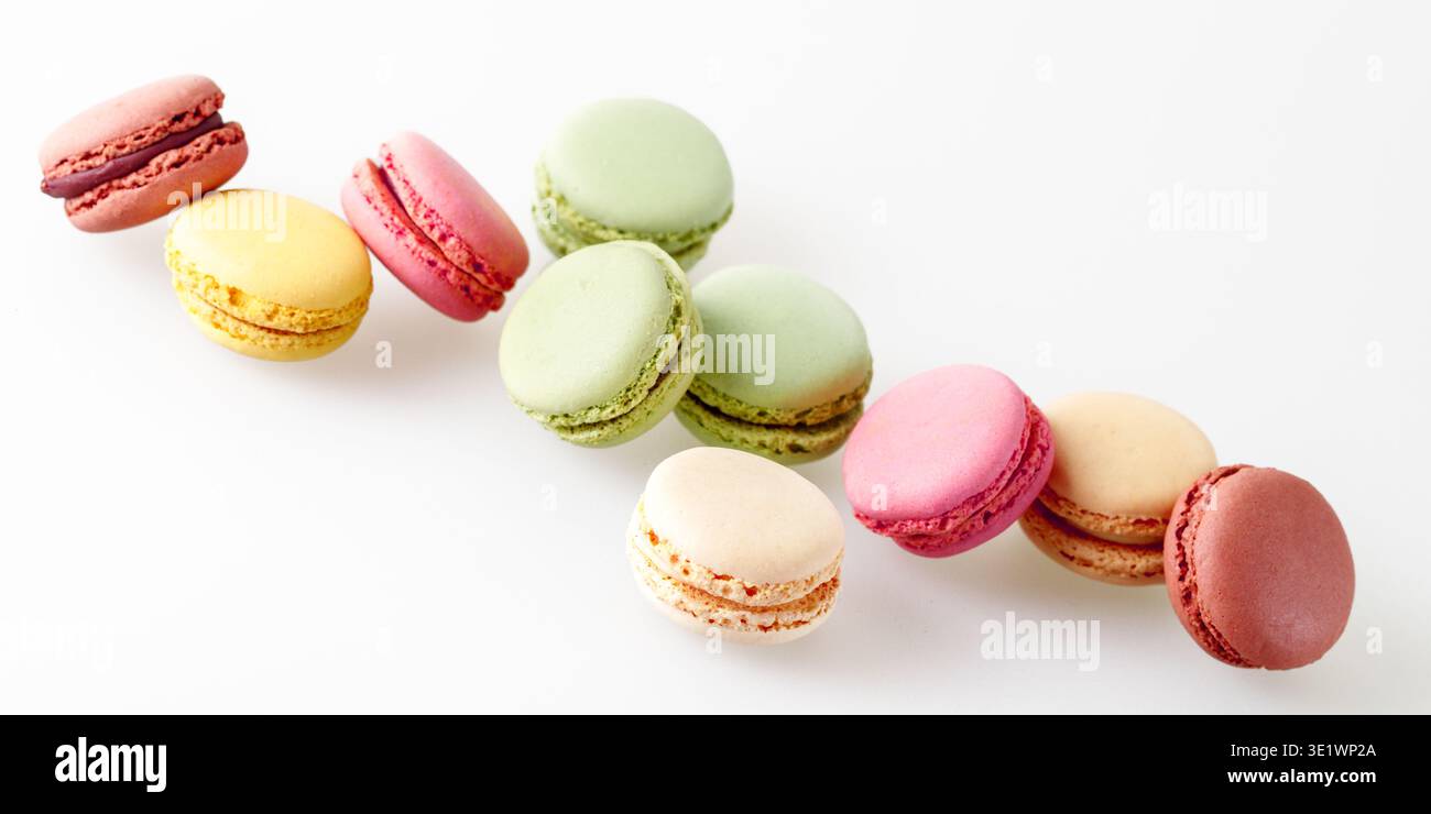Biscotti francesi dolci e colorati macaron macaron che volano su sfondo chiaro e neutro. Striscione per pasticceria con spazio per copie Foto Stock