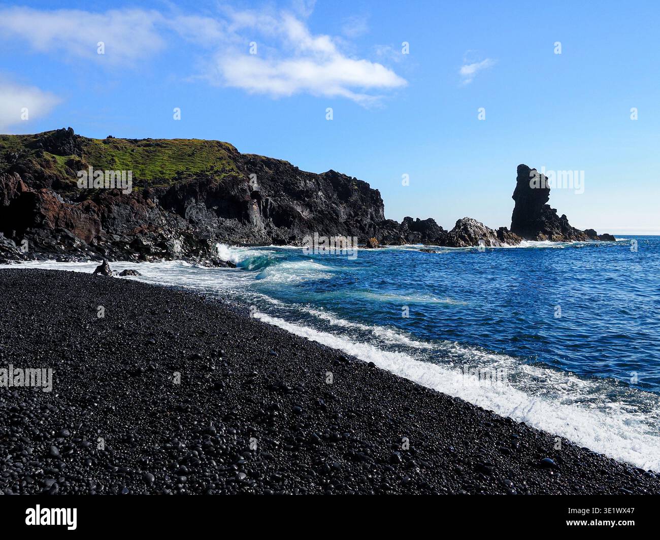 Bellissima spiaggia di Djupalonssandur. Situato sulla costa meridionale dell'Islanda. Formazioni rocciose basaltiche e sabbia nera bagnata e ciottoli. Oceano Atlantico blu. Foto Stock