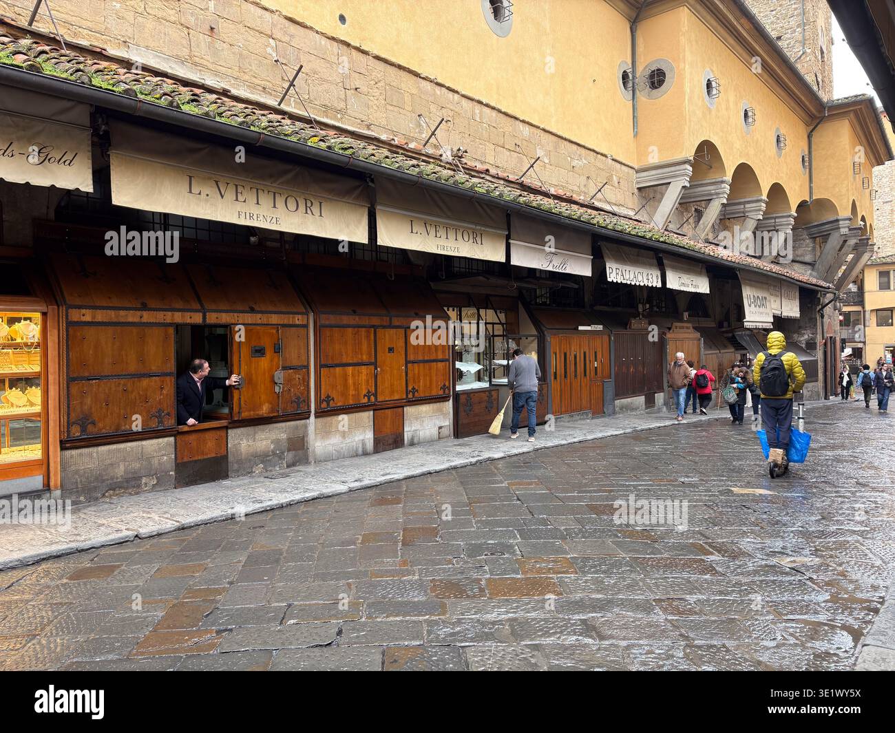Ponte Vecchio, Firenze Italia. Negozi di gioielli sul ponte medievale che si preparano per il commercio mattutino su ciottoli bagnati, partenza presto. Foto Stock
