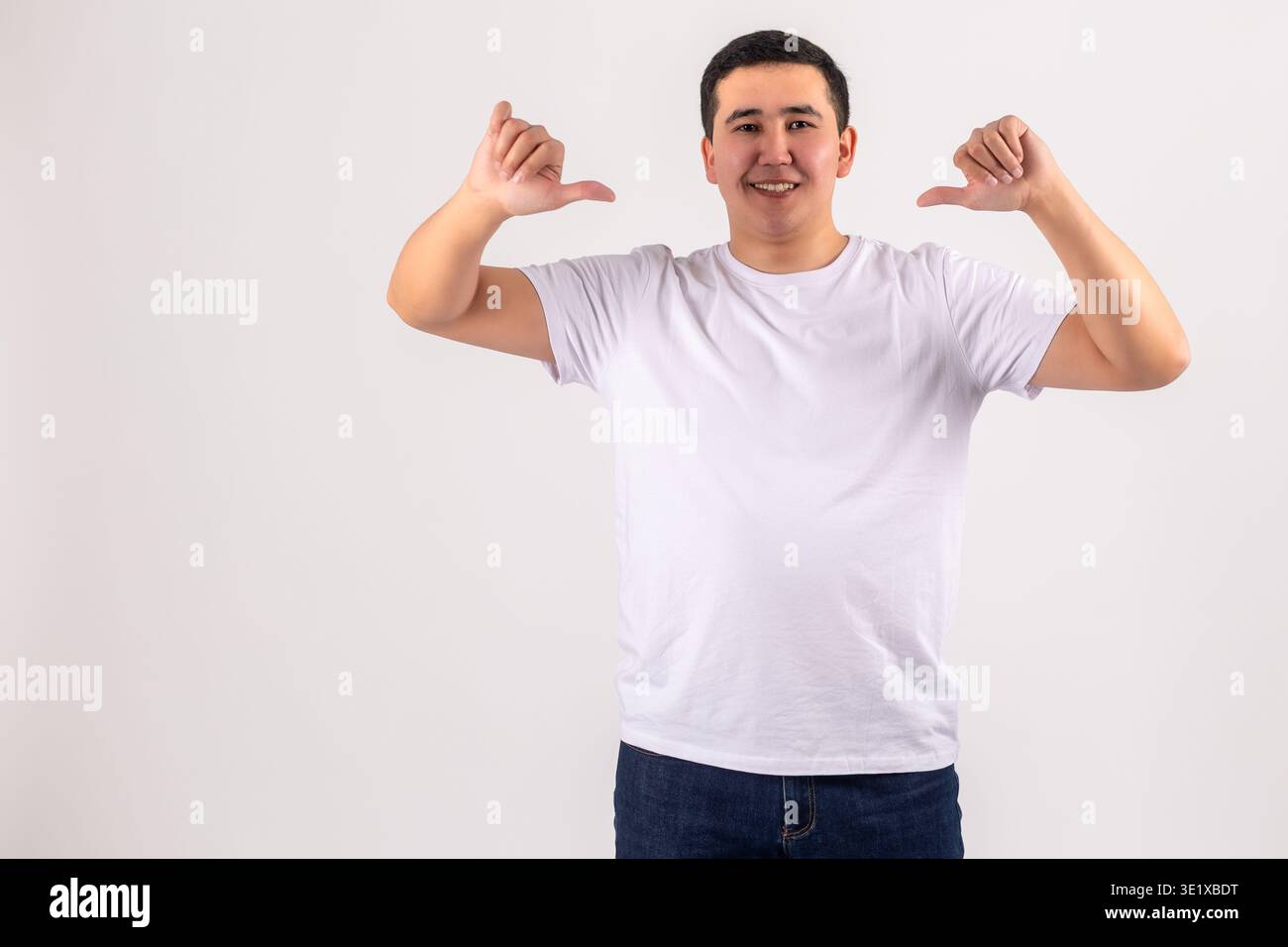 Uomo sicuro di sé con t-shirt bianca che punta su se stesso con i pollici Foto Stock