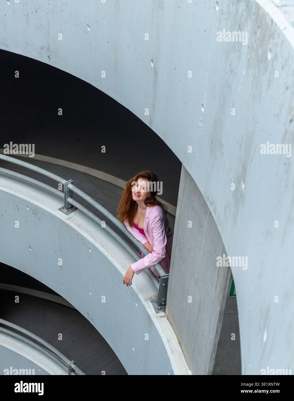 Una giovane donna sorridente che si gode una pausa nel parcheggio, sopra la vista Foto Stock