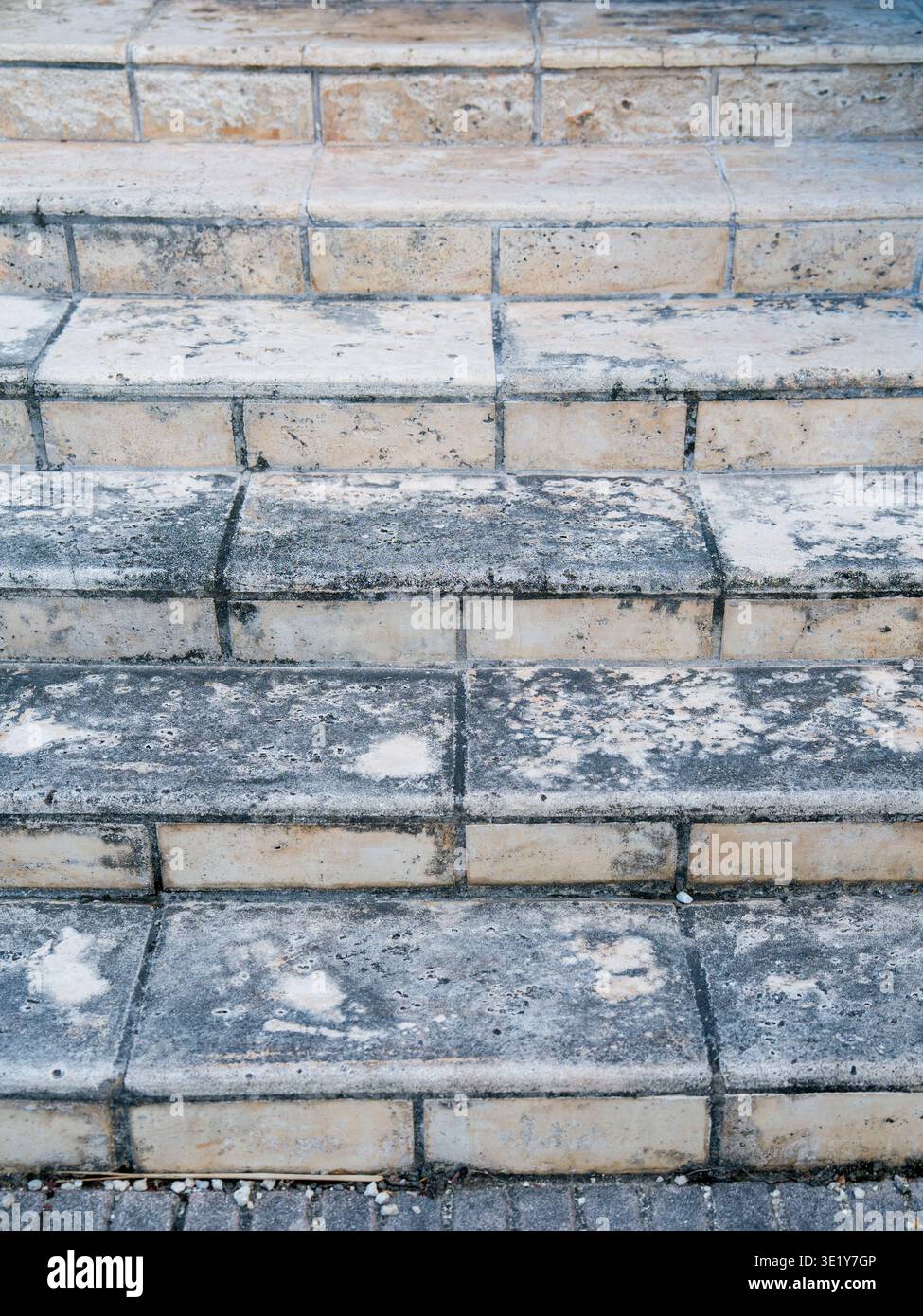 Primo piano di scale in pietra grigia intemprate con macchie d'acqua scura e superficie snodata ruvida in un ambiente architettonico urbano moderno. Foto Stock