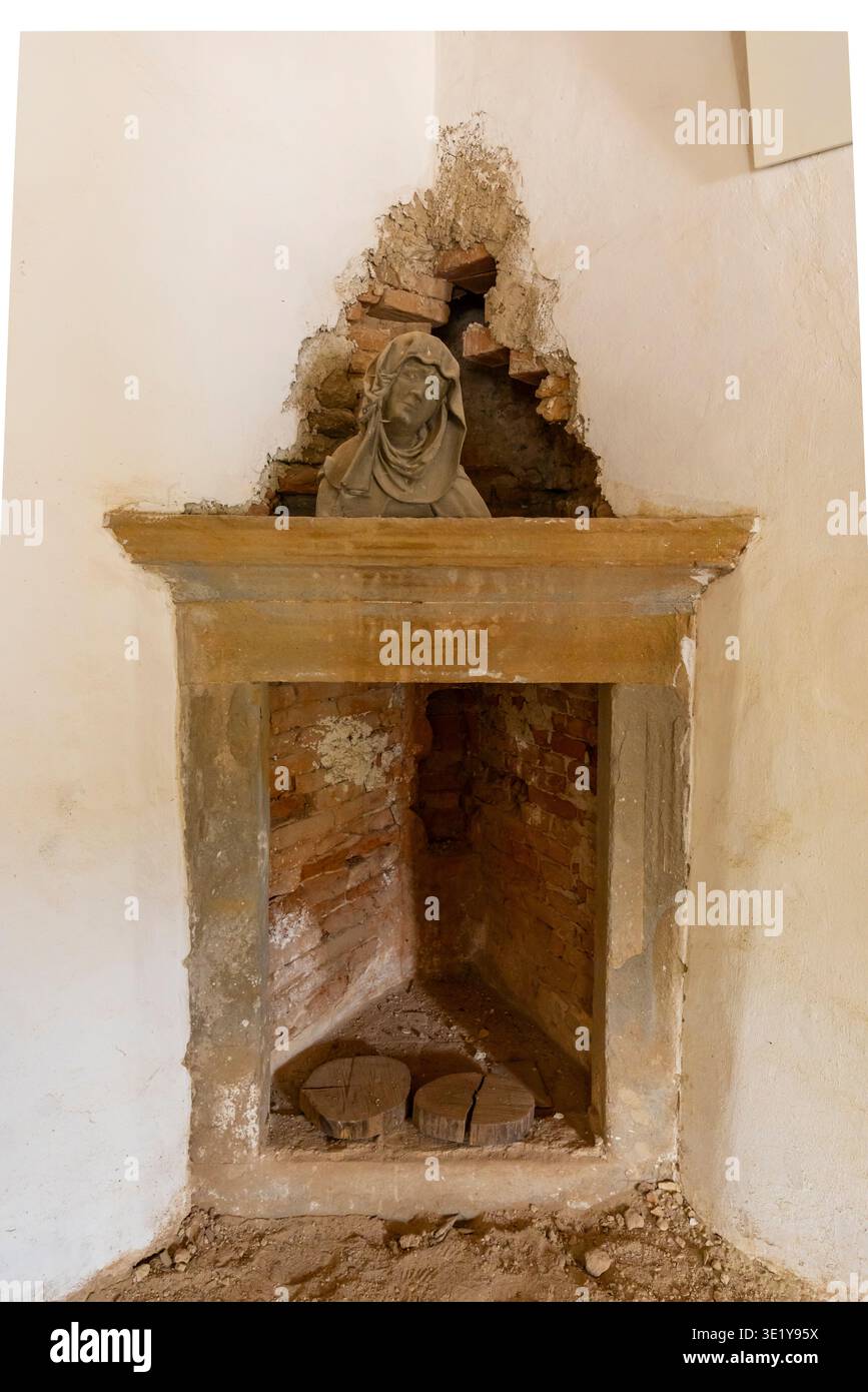 Antico busto scultoreo adagiato in un camino ad angolo con pareti in decadenza, rivelando una struttura in mattoni Foto Stock