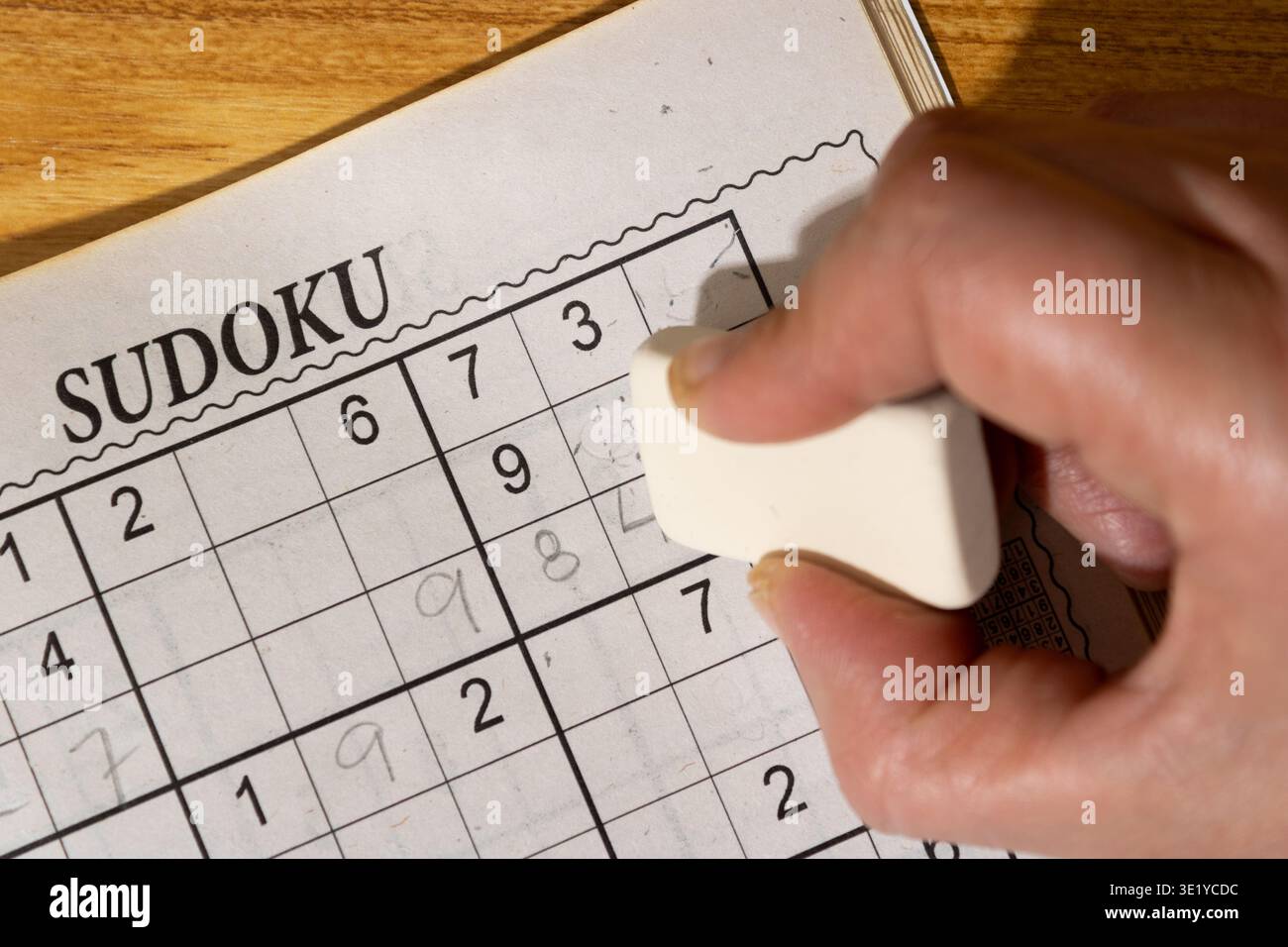 Primo piano di una persona che gioca a Sudoku che ha commesso un errore e l'ha cancellato con una gomma a matita. Foto Stock