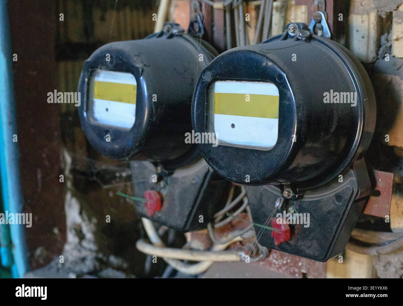 Due contatori elettrici vintage sigillati in un pannello elettrico in un vecchio edificio industriale. I misuratori sono collegati alla rete elettrica e al display el Foto Stock