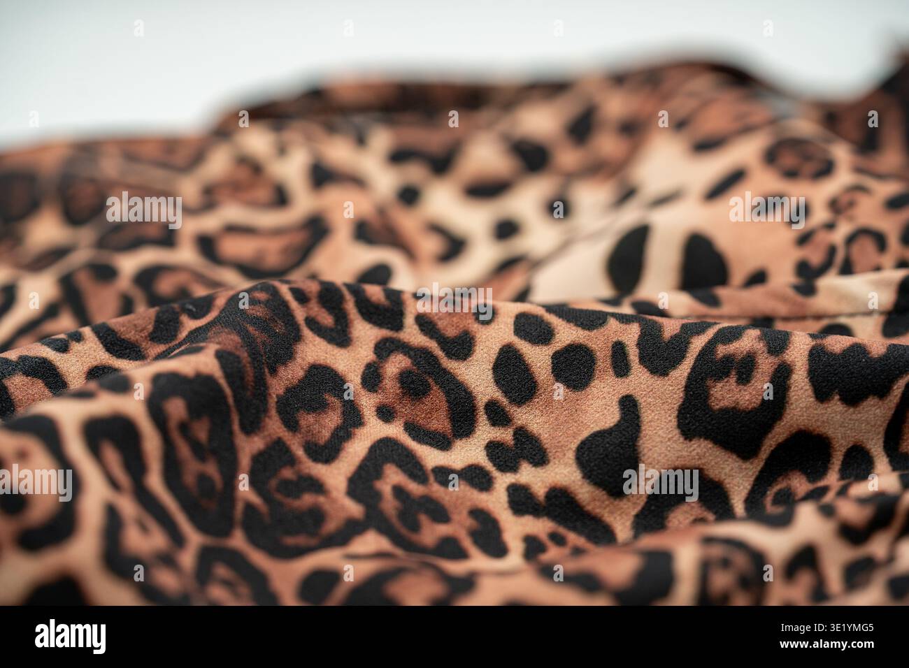Primo piano della trama in tessuto con stampa leopardata con pieghe e motivi morbidi. Foto Stock