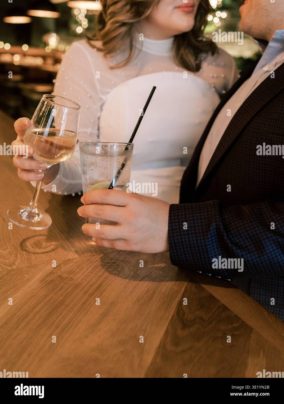 Coppia che gusta bevande in un bar durante un raduno sociale alla sera con un'atmosfera calda e una luce soffusa Foto Stock