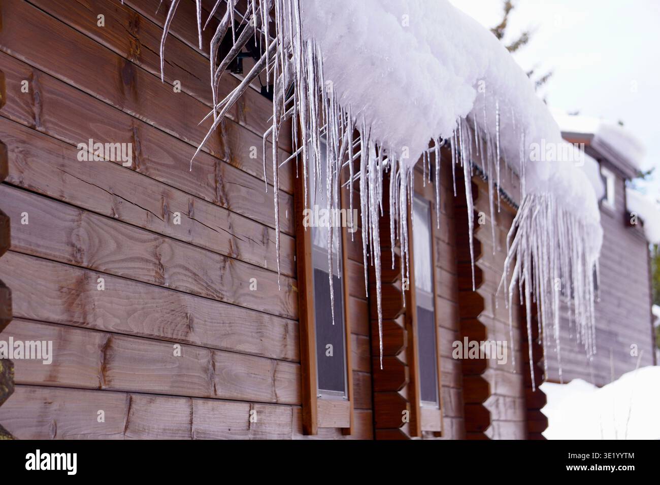 In inverno, a Island Park Idaho, si sono formati lunghi ghiacciai e neve taglienti sul tetto di una cabina Foto Stock