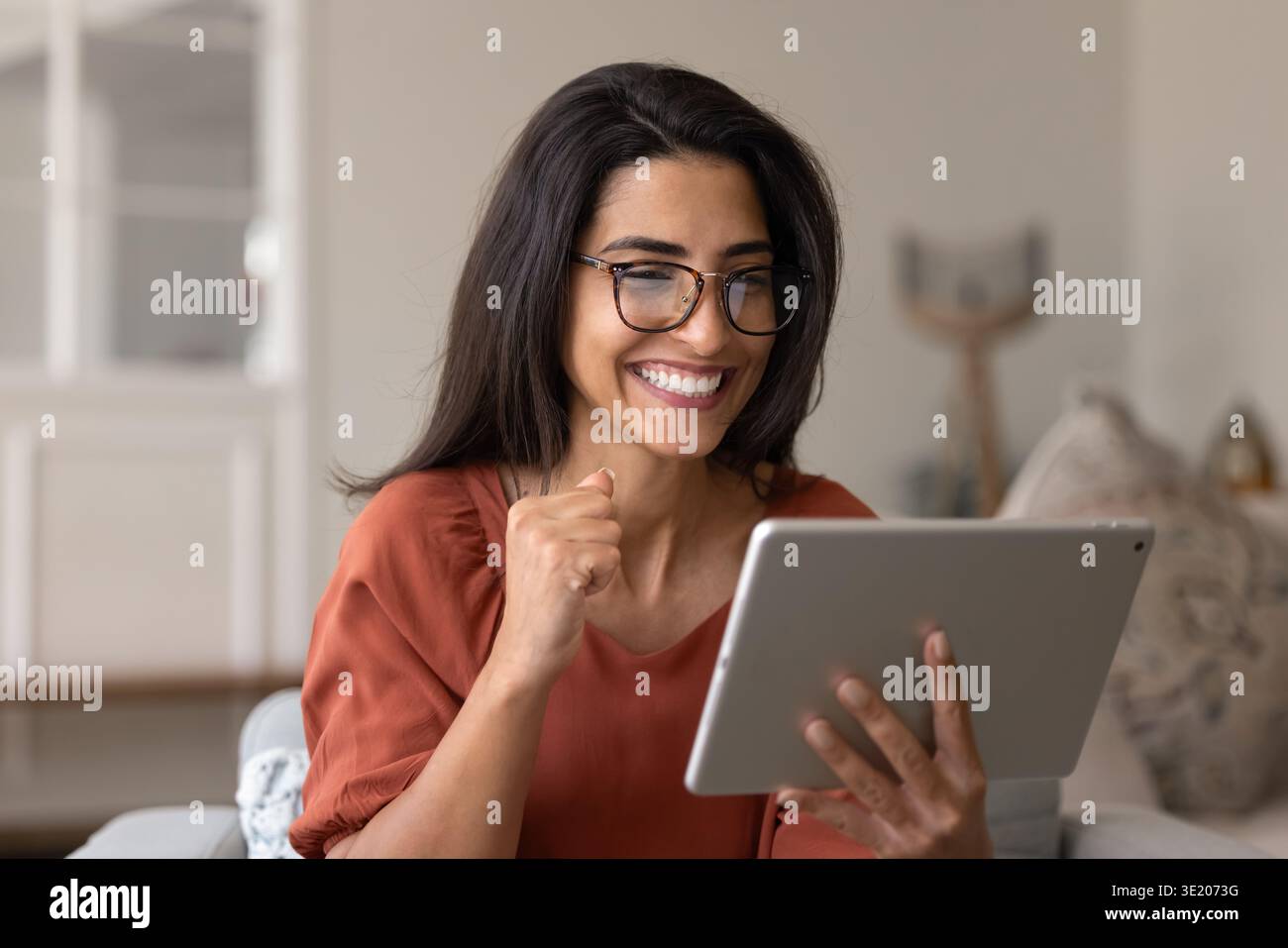 Felice latina che legge grandi e incredibili notizie su tablet Foto Stock