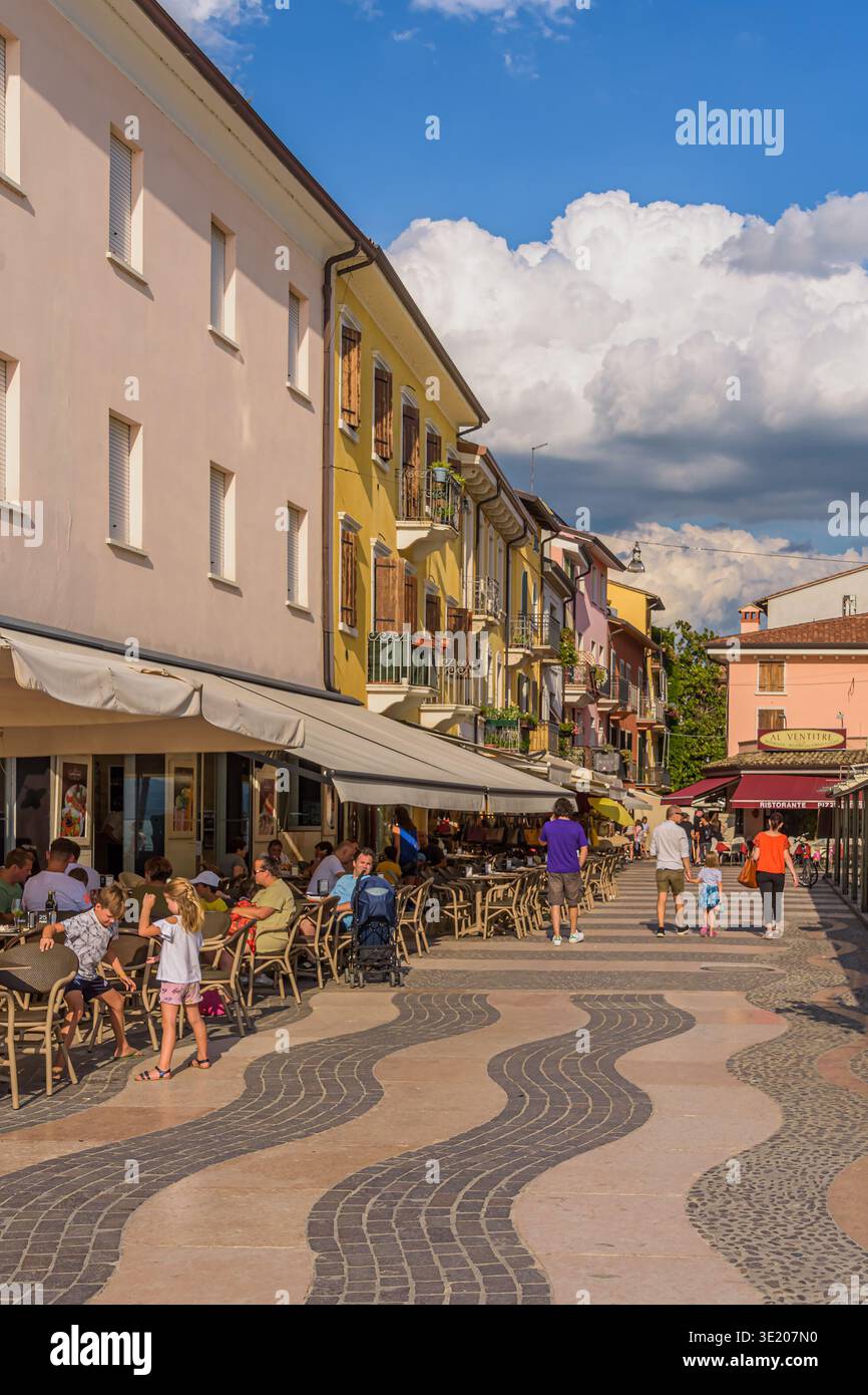 Persone sul lungomare, con motivi ondulati per strada, a Lazise sul Lago di Garda, Italia Foto Stock