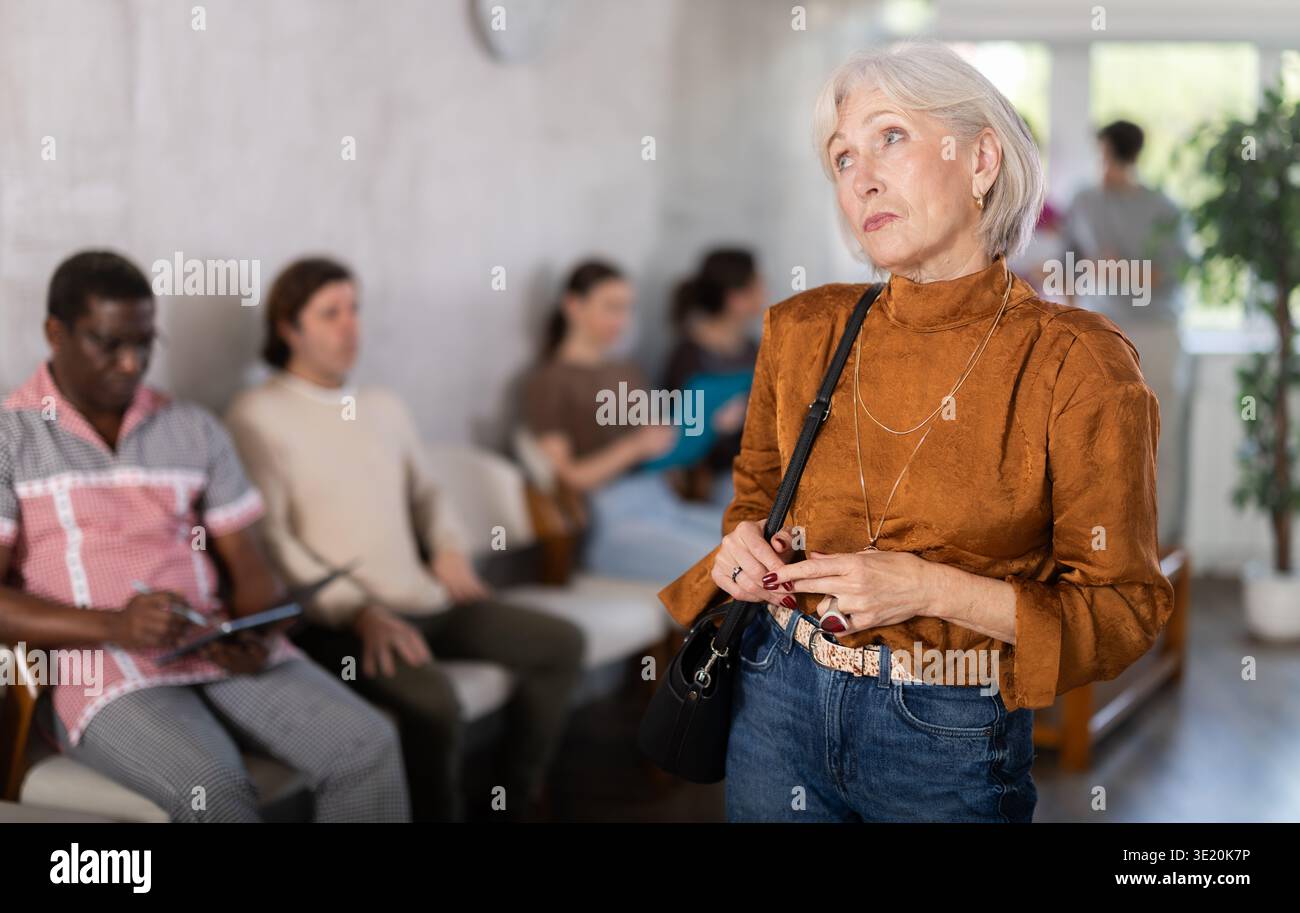 Donna matura in piedi nell'area della reception Foto Stock