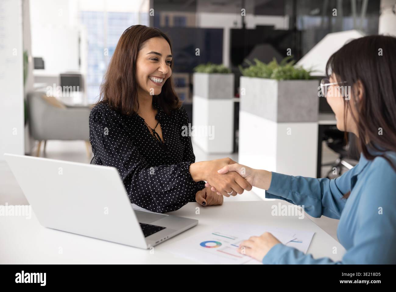 Allegra giovane donna d'affari mediorientale che stringe la mano a un consulente asiatico Foto Stock