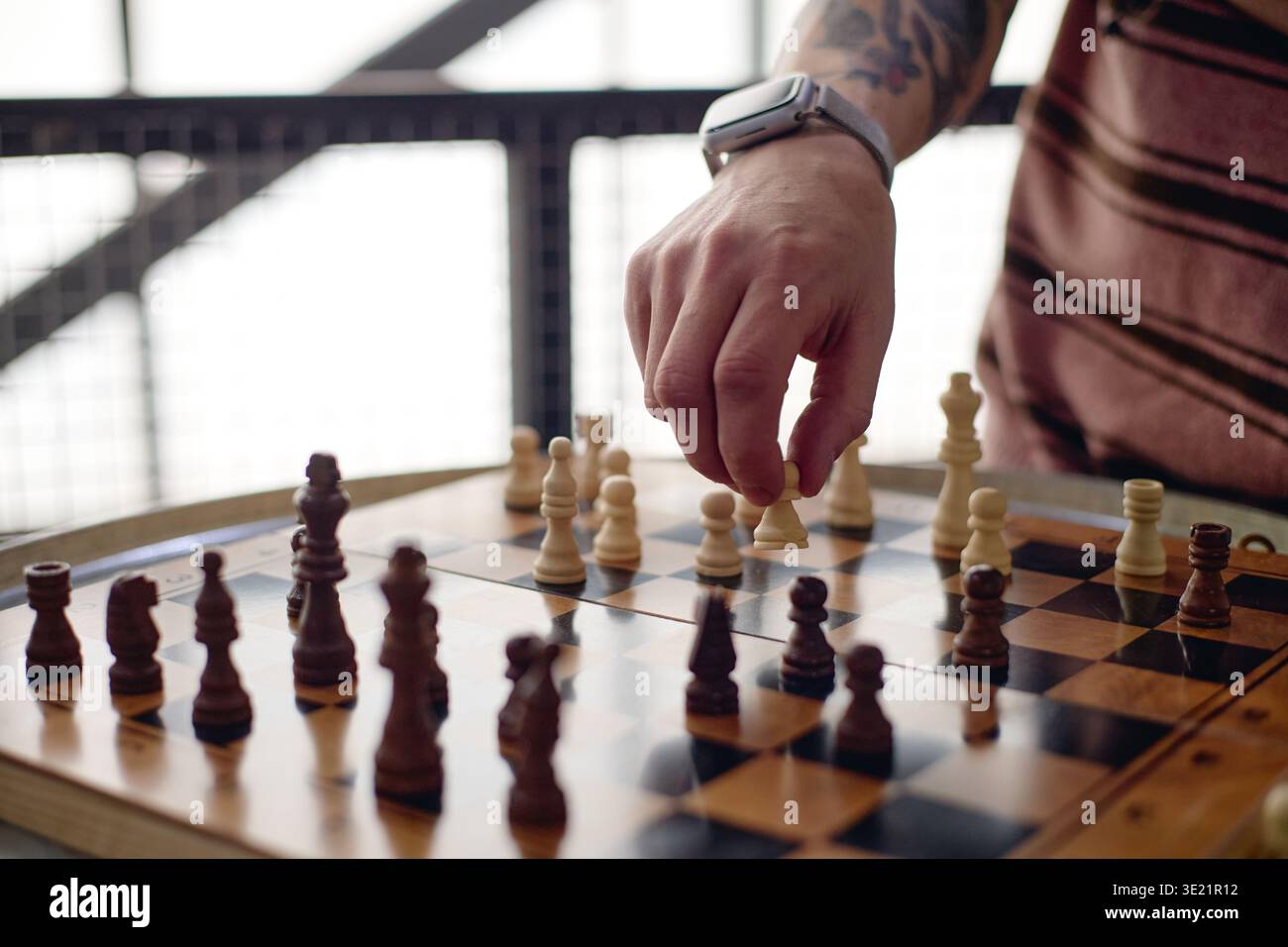 Giovane adulto che gioca a scacchi che fa una mossa strategica Foto Stock