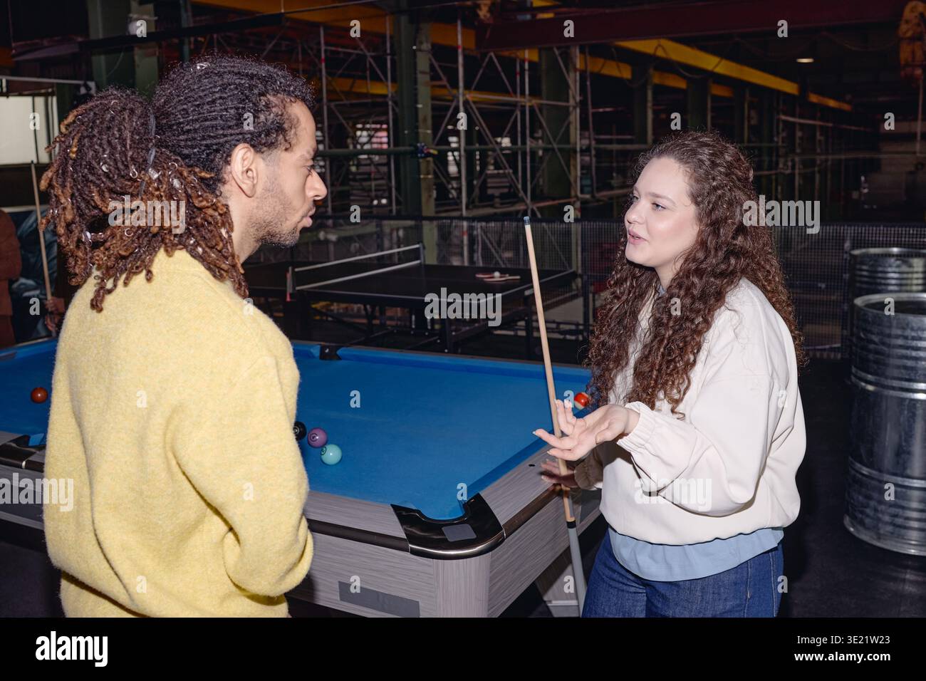 Giovane donna che spiega le regole dei biliardi a Young Black Man al chiuso Foto Stock