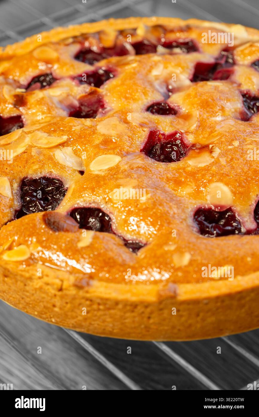 Torta bakewell alla ciliegia fatta in casa con mandorle, rinfrescata su uno sfondo di griglia di raffreddamento in metallo. Foto Stock