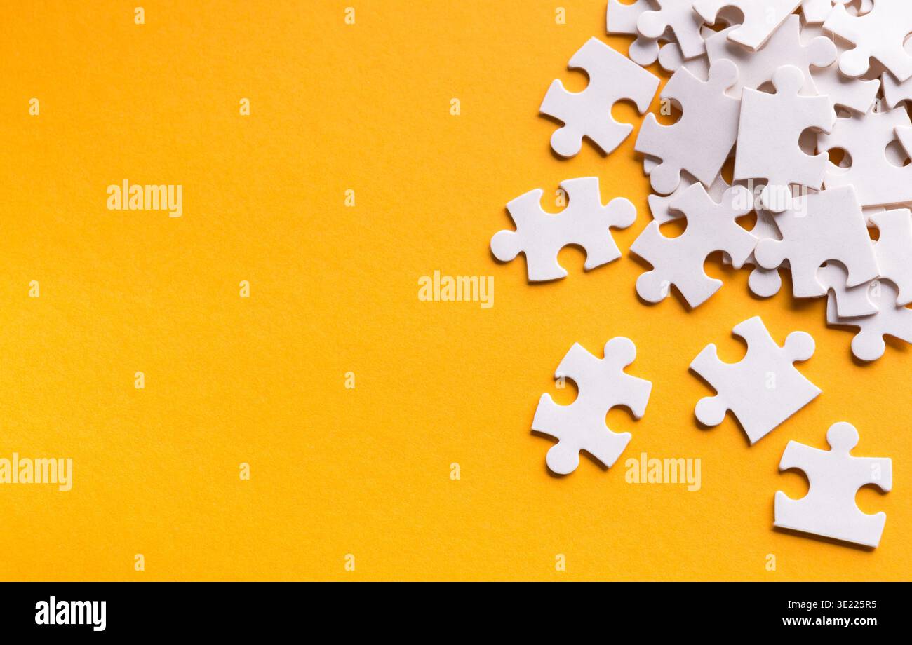 Collezione di pezzi di puzzle bianchi visualizzati su uno sfondo arancione brillante in un layout creativo Foto Stock