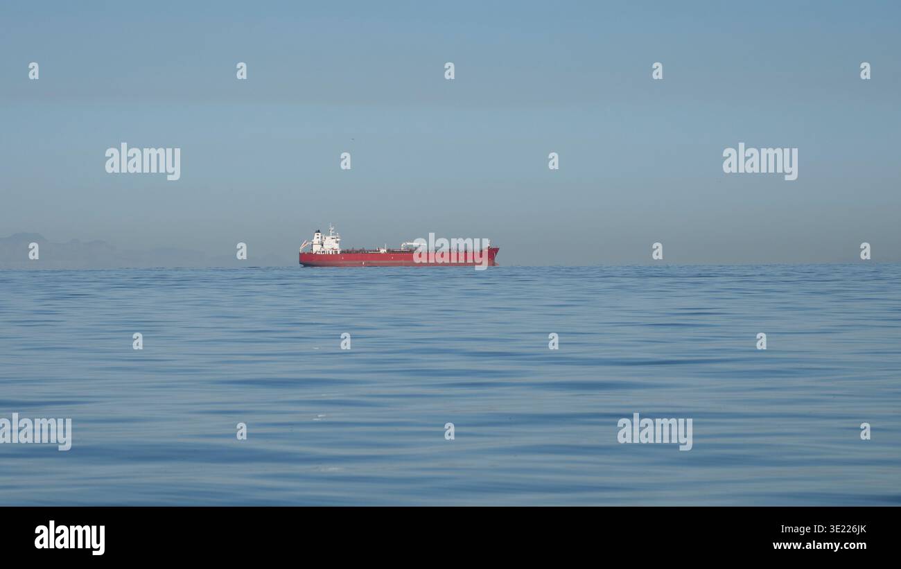 La nave da carico rossa naviga sull'oceano blu calmo sotto il cielo limpido. Canada Foto Stock