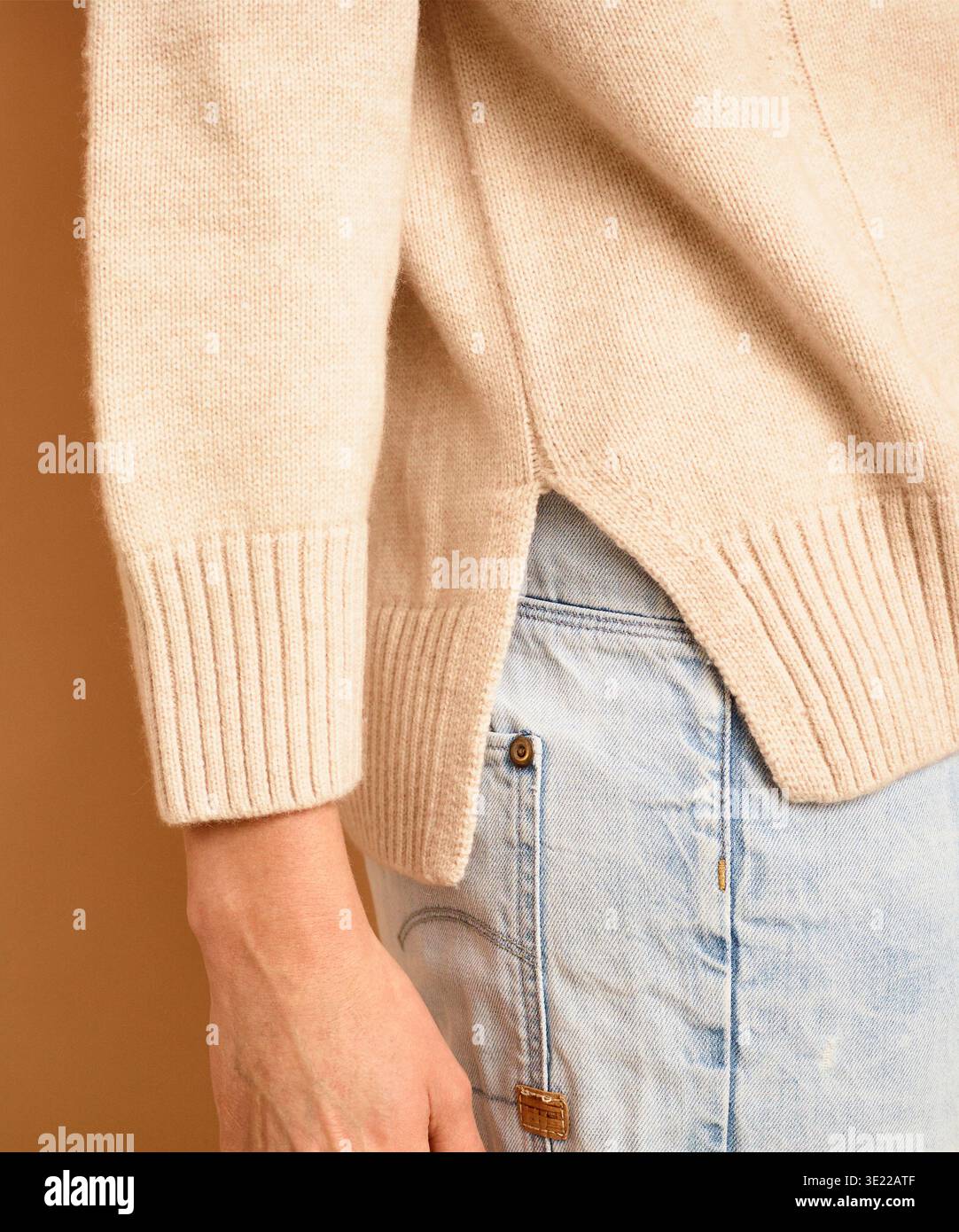 Primo piano di una persona che indossa un maglione beige e pantaloni in denim azzurro. Germania Foto Stock