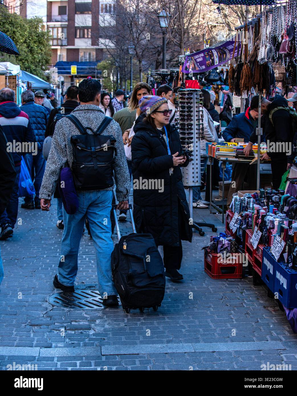 I visitatori curiosano tra le bancarelle colorate del mercato lungo il Campillo del Mundo Nuevo, catturando l'atmosfera vivace dell'iconico Rastro di Madrid Foto Stock