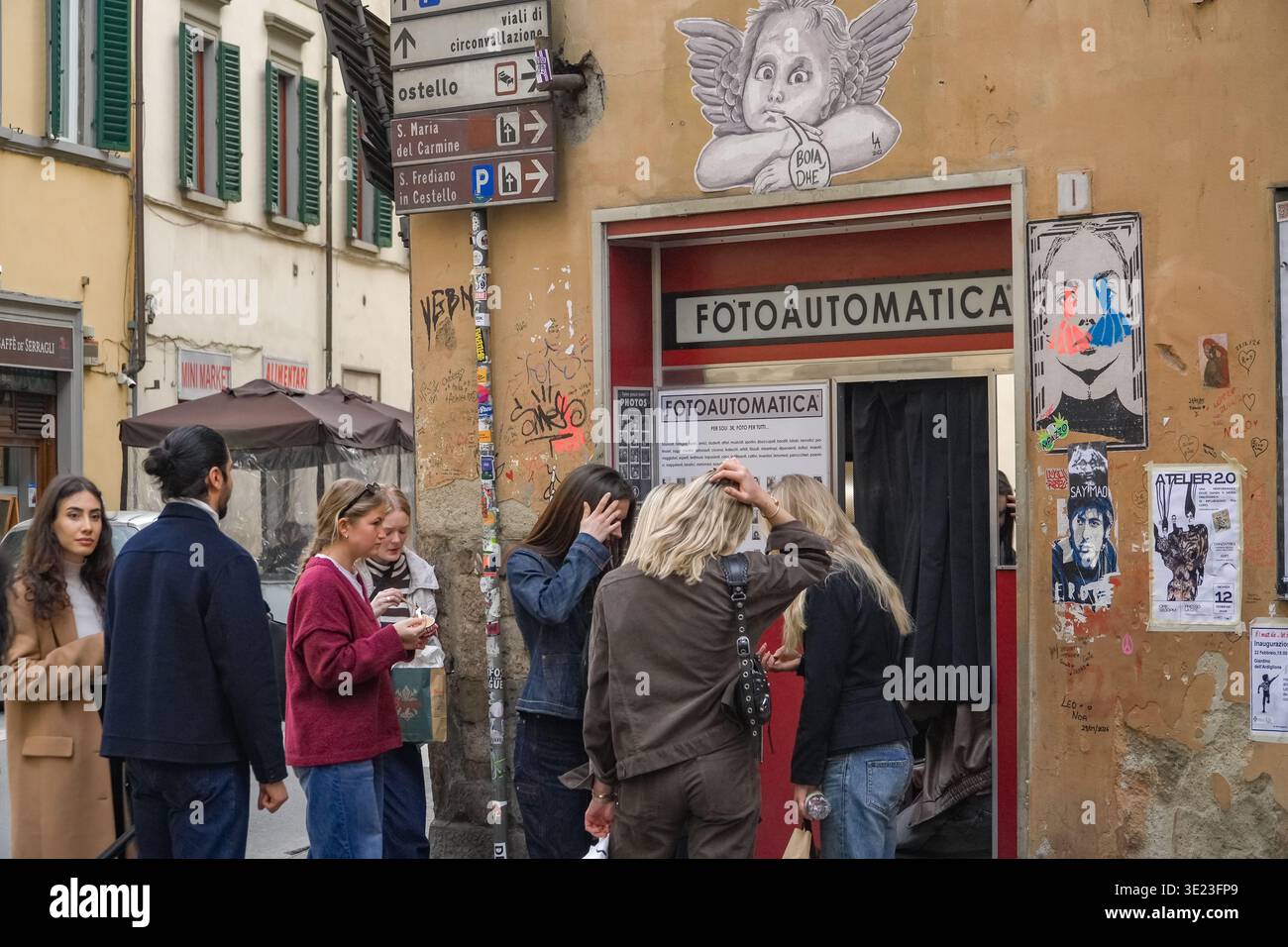 Cabina fotoautomatica. Firenze, Italia. I turisti si preparano per scattare foto istantanee in bianco e nero in un ambiente urbano affollato con graffiti. Foto Stock