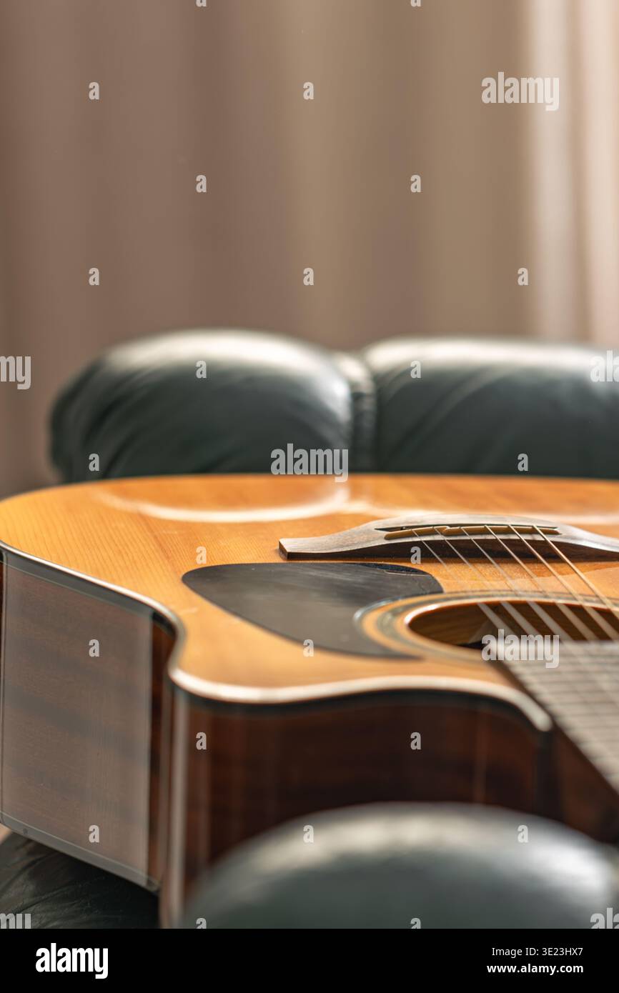 Primo piano con chitarra acustica in interni caldi. Sottofondo musicale minimo. Foto Stock