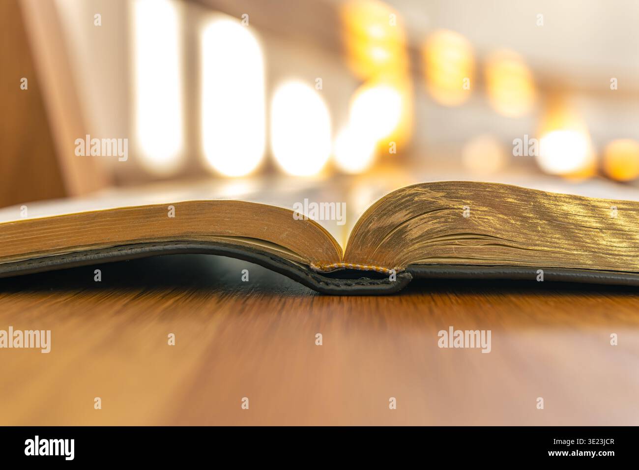 Bibbia aperta a basso angolo su legno. Texture dorata. Foto Stock