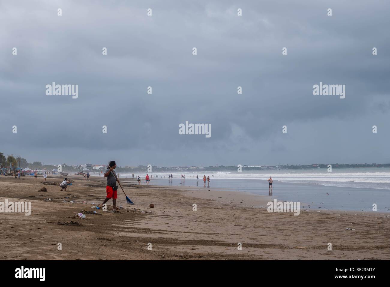 Uomo che pulisce Kuta Beach a Bali durante il tempo coperto Foto Stock