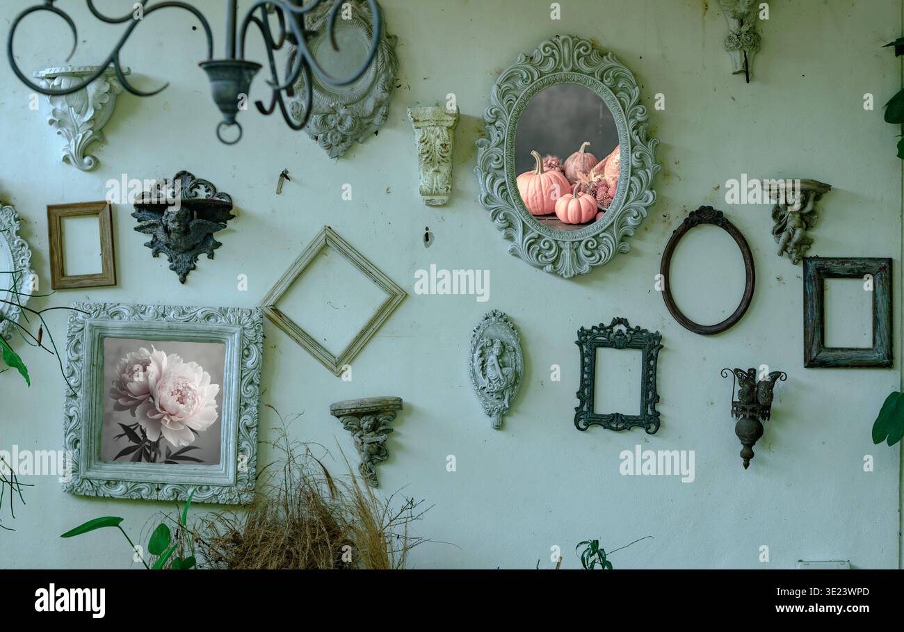 Elegante muro rustico decorato con cornici antiche assortite, caratterizzato da un romantico dipinto di peonia e zucche autunnali in un ambiente nostalgico Foto Stock