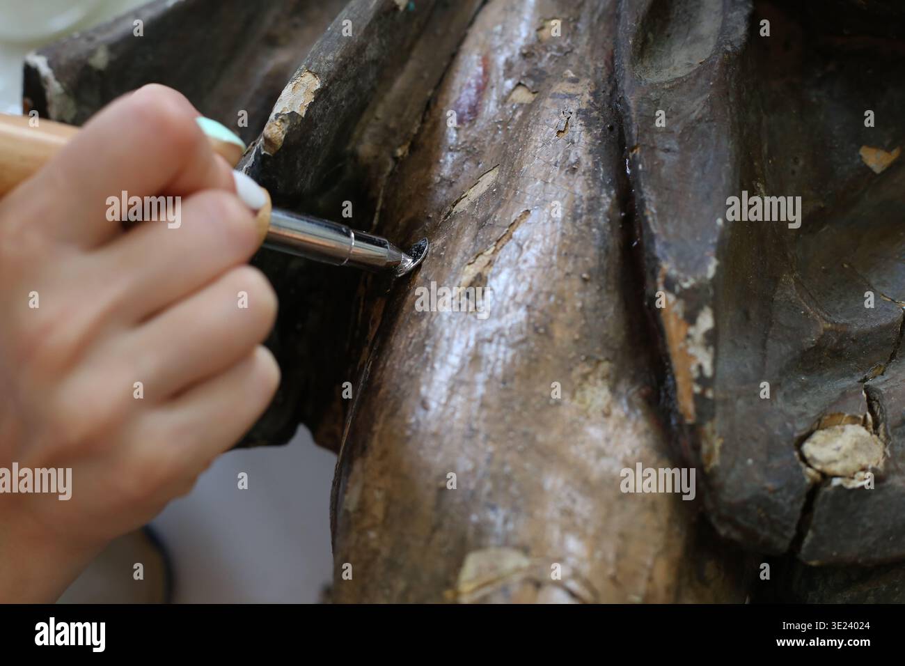 Art Conservator applica la luce ultravioletta durante il restauro di un frammento di tela di legno in un ambiente studio specializzato. Foto Stock