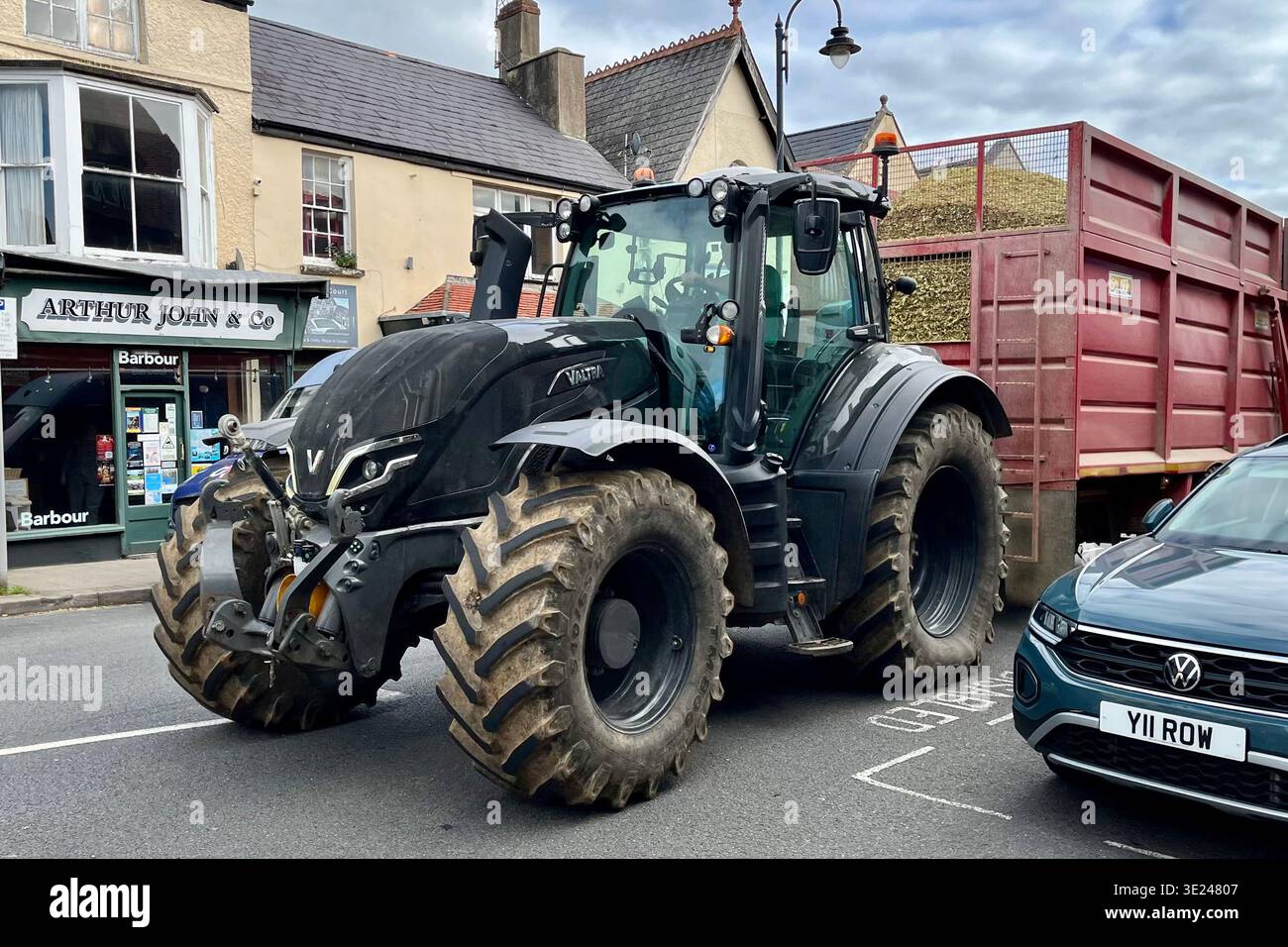 Un trattore nero con rimorchio che attraversa il centro di Cowbridge. Cowbridge, vale of Glamorgan, Galles, Regno Unito. 17 ottobre 2025 - Immagine stock catturata con smartphone