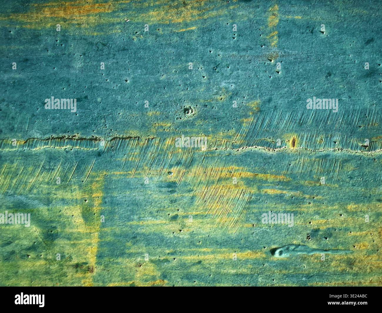 Vista ravvicinata di una superficie in legno angosciato con strati di vernice blu e giallo testurizzati che mostrano usura e graffi Foto Stock