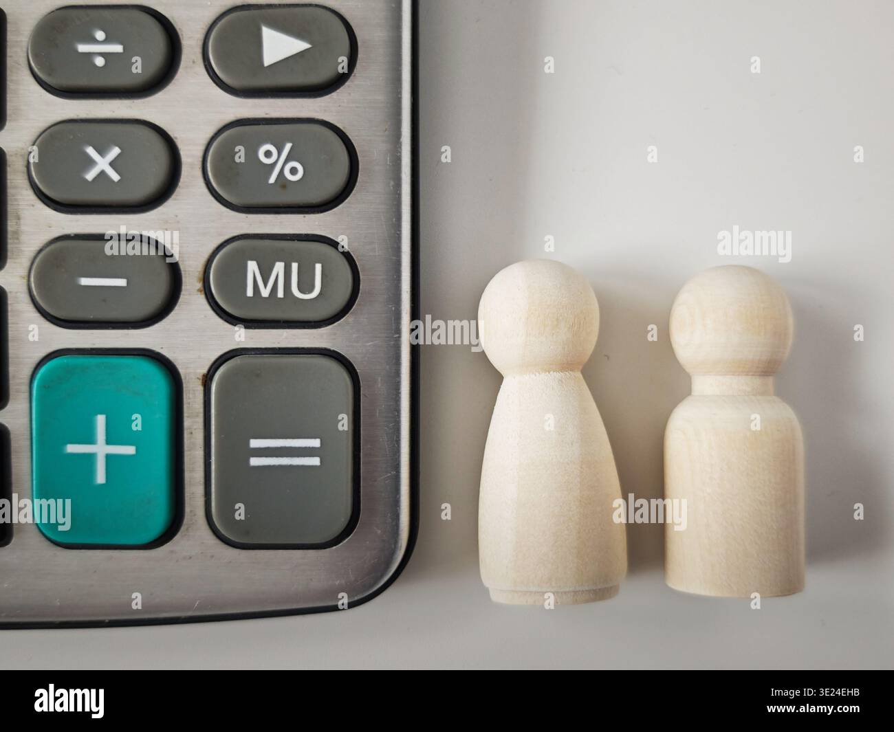 Le famiglie gestiscono i budget con calcolatrici e cifre in legno per pianificare spese, entrate e risparmi per le esigenze finanziarie quotidiane. Foto Stock