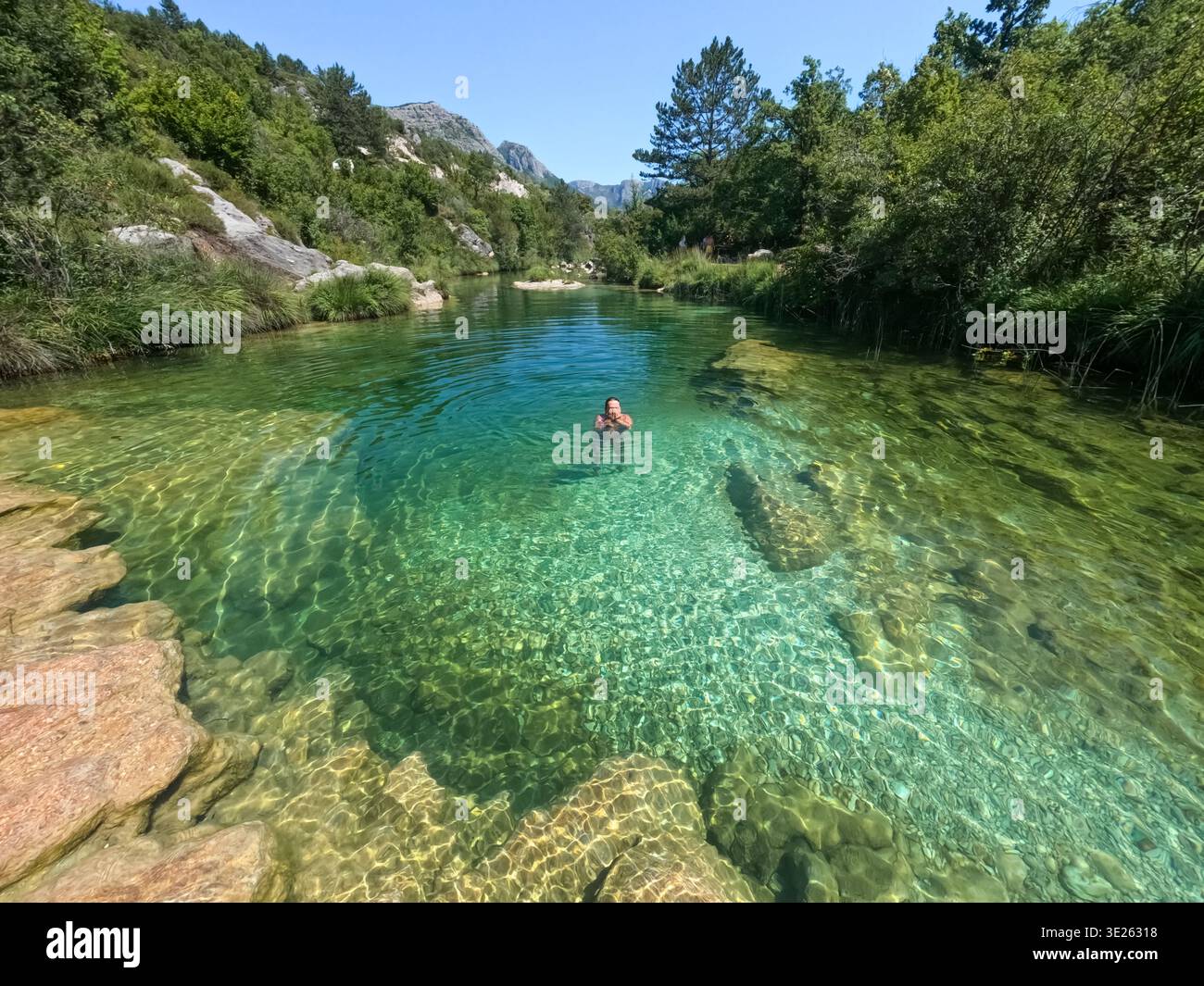 Donna che si pulisce il viso dopo essersi immersa nel fiume turchese Susica vicino a Trebinje Foto Stock