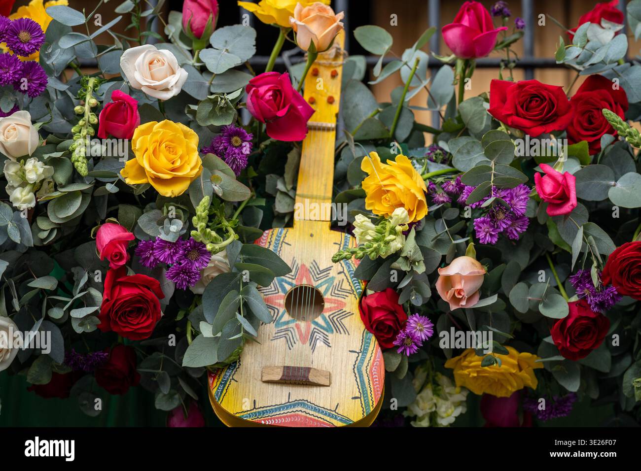 Festival De Flores - Antigua Guatemala - Una chitarra in legno dipinta annidata in una lussureggiante disposizione di rose rosse, gialle e crema, assaggi viola ed eucali Foto Stock