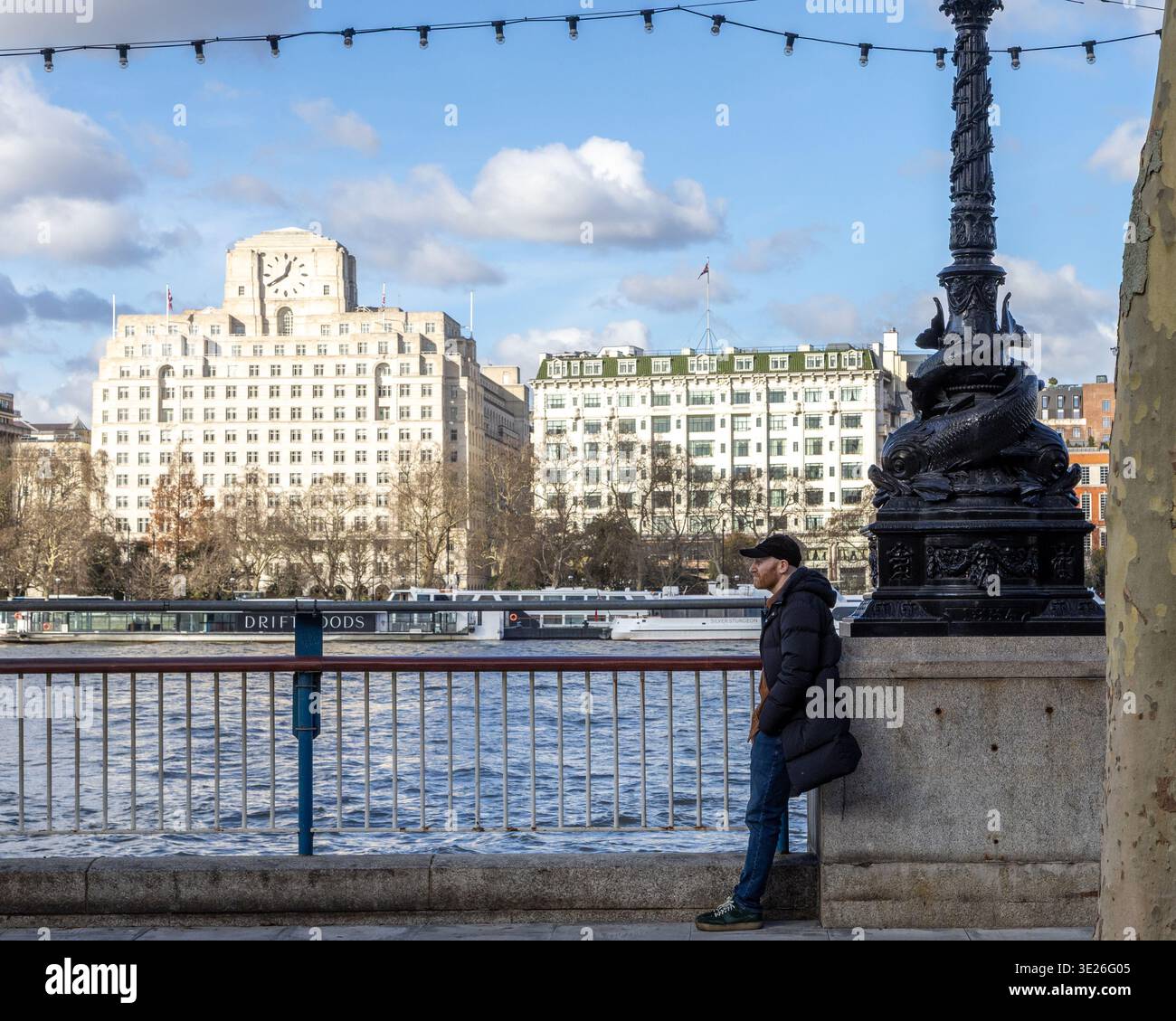 Uomo appoggiato sul lampione sul fiume tamigi, londra, acriss frim Shell Mex House Foto Stock