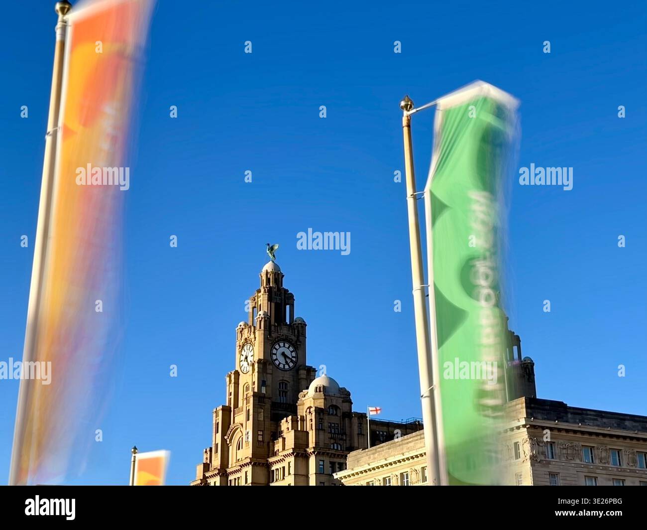 Royal Liver Building e visita le bandiere di Liverpool che soffiano nel vento contro un cielo blu vivace Foto Stock
