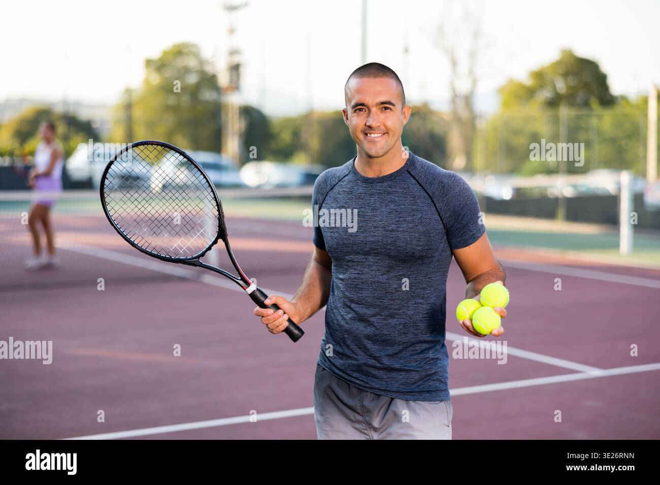Tennista maschile molto vivace che posa per la macchina fotografica con racchetta da tennis e palla Foto Stock
