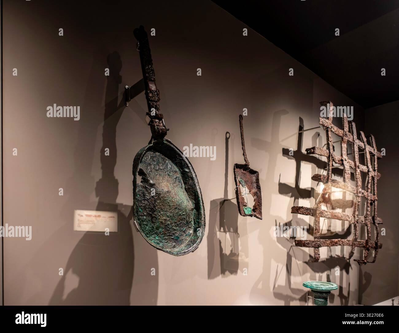 Antichi utensili in ferro e bronzo, tra cui una grande padella e una grata, esposti al Museo foro Romano Molinete di Cartagena, Spagna. Foto Stock